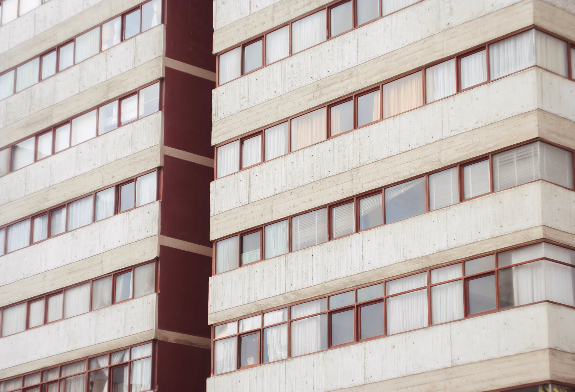 Fachada de un edificio de departamentos con ventanas de marco rojo